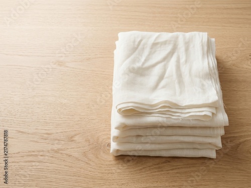 Stack of clean white folded towels on a light wooden table surface