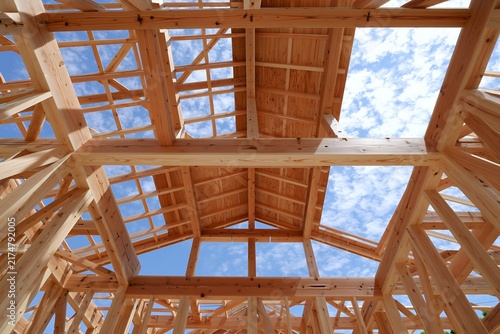 Obraz w ramie 木材が組まれた新築住宅の構造体と澄み渡る青空