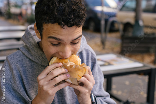 Young man enjoying a delicious burger outdoors