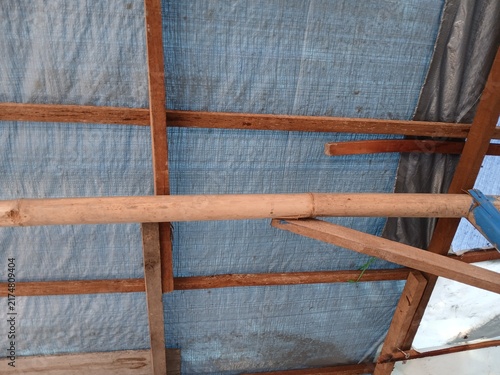 Foto Wooden Rafters and Bamboo Structure with Blue Tarpaulin Roof Canopy Background