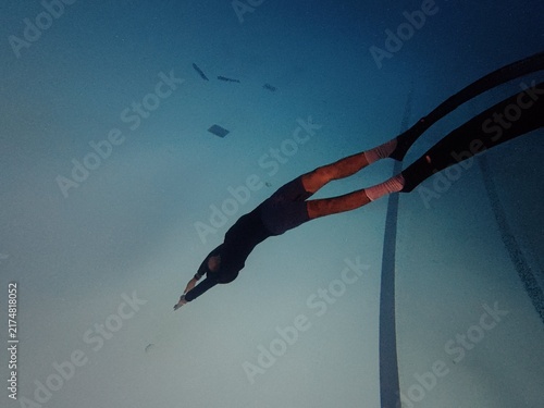 Freediver in streamline position diving underwater in blue swimming pool