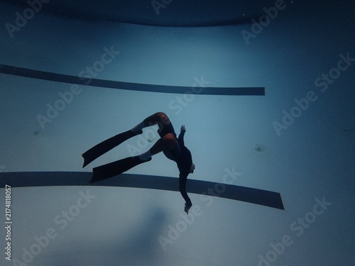 Freediver doing backward flip underwater above swimming pool lane lines