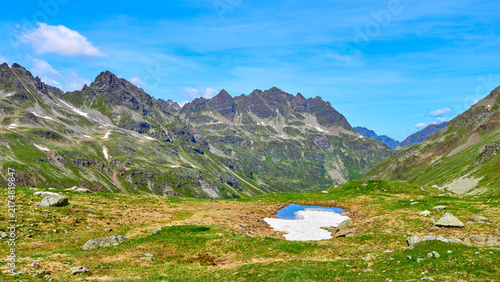 Konstfotografi Tümpel mit letztem Schneefeld vor zerklüfteten Alpengipfeln im Silvretta-Gebiet
