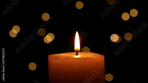 Candle burns Isolated On Black background with Christmas Lights Defocused Bokeh.
