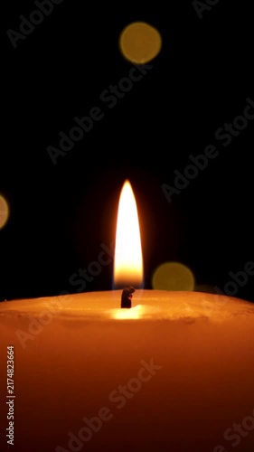 Candle burns Isolated On Black background with Christmas Lights Defocused Bokeh.