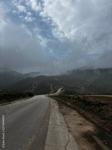 Scenic road in Salalah, Oman, winding through the lush green Dhofar Mountains during Khareef season, with misty hills, cloudy skies and beautiful natural surroundings. the gulf country near to Kerala