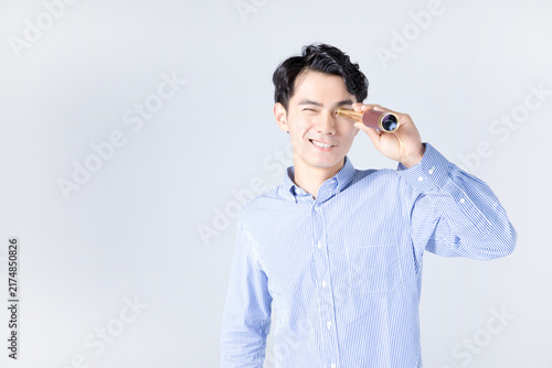 Young man looking through small telescope with smile in studio