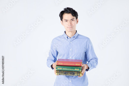 Young man holding stack of books in studio