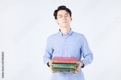 Confident young man holding stack of books in studio