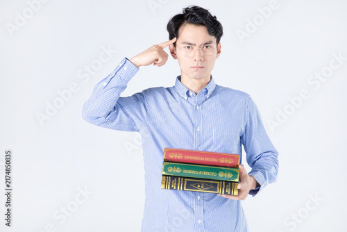 Young man holding books and pointing to his temple in studio