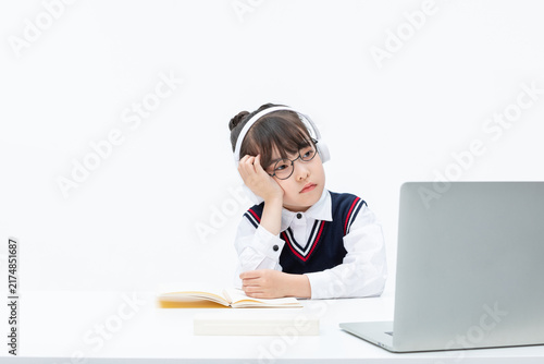 Bored schoolgirl studying online with laptop headphones and book
