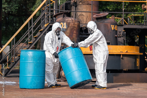 фотографія Hazmat workers tilting and moving a chemical storage drum together during hazard
