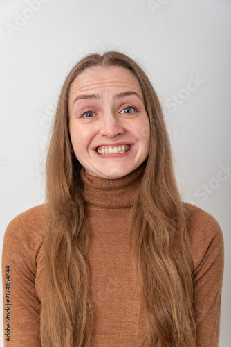 Obraz na plátně Young woman with long brown hair making a funny grimace, wrinkling her nose and