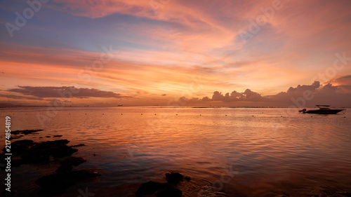 A gorgeous sunset over the ocean on an idyllic scenic beach in Mauritius. The warm evening light illuminates the tranquil sea and sandy shoreline, creating a peaceful tropical landscape