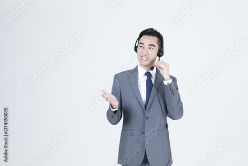Картината върху платно Smiling businessman with headset speaking and gesturing on light background