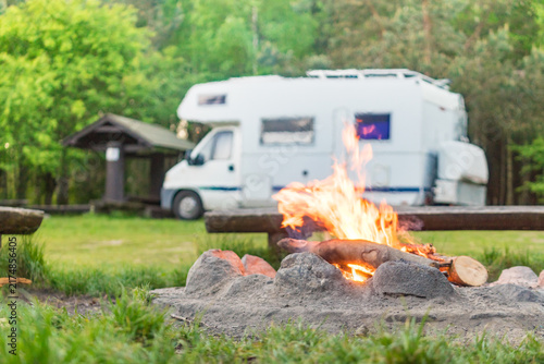 Camping on nature with cozy campfire and motorhome in serene forest setting