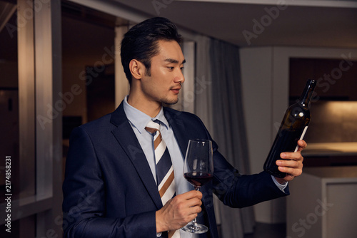 Photography Elegant businessman examining red wine indoors