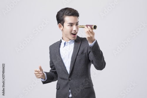 Bild auf Leinwand Excited businessman looking through small telescope in studio