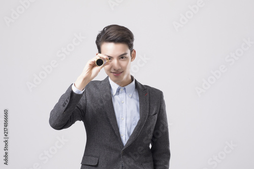 Fotografie Smiling businessman looking through monocular with vision concept