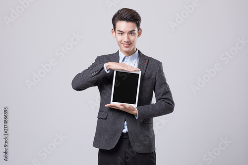 Smiling businessman presenting blank tablet screen in studio