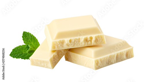Three stacked pieces of creamy white chocolate sit beside fresh green mint leaves, all against a clean black background