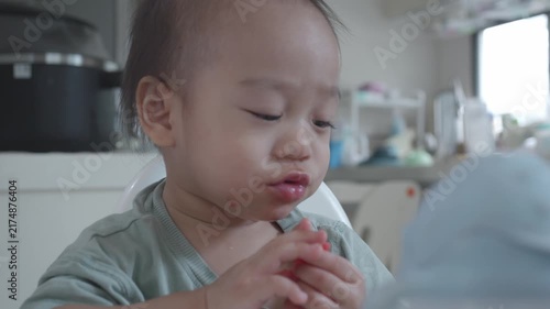 A young child sits at a table, focused on a snack in a well-lit kitchen. The scene captures a moment of curiosity and joy, highlighting the innocence of childhood in a cozy home setting.
