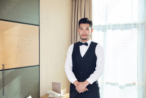 фотографія Professional hotel butler standing in guest room by window
