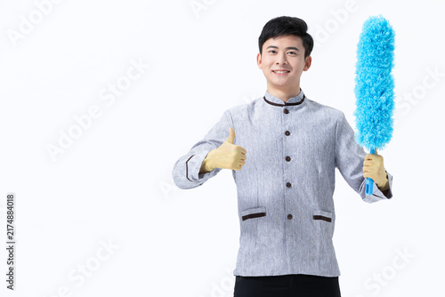 Bild auf Leinwand Smiling cleaner holding feather duster and giving thumbs up on white background
