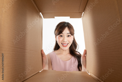 Konstfotografi Happy young woman opening cardboard box and looking inside