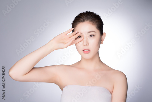 Foto Young woman with clear skin making eye gesture in beauty skincare portrait