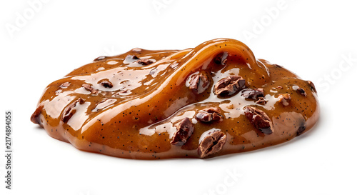 Macro shot of glossy caramel balm swatch with roasted cacao nibs on white background