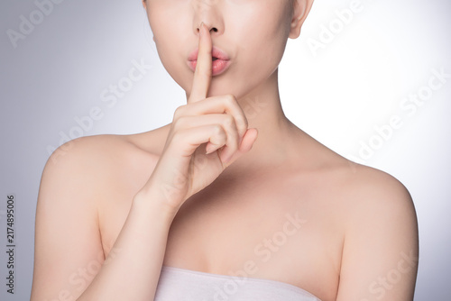 Obraz na płótnie Young woman with finger on lips making silence gesture