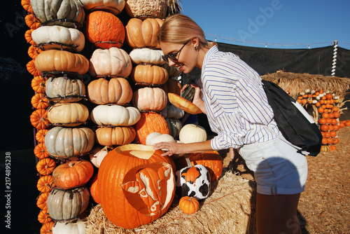 Woman with orange pumpkins at outdoor farmer market. Halloween pumpkins