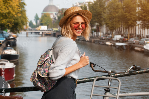Happy traveler girl enjoying Amsterdam city. Smiling woman on Amsterdam canal, Netherlands, Europe