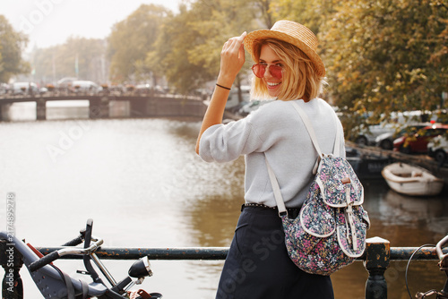 Happy traveler girl enjoying Amsterdam city. Smiling woman on Amsterdam canal, Netherlands, Europe