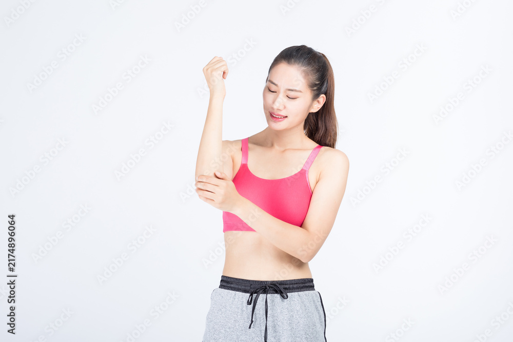Fototapeta premium Young woman with elbow pain in sportswear on light background