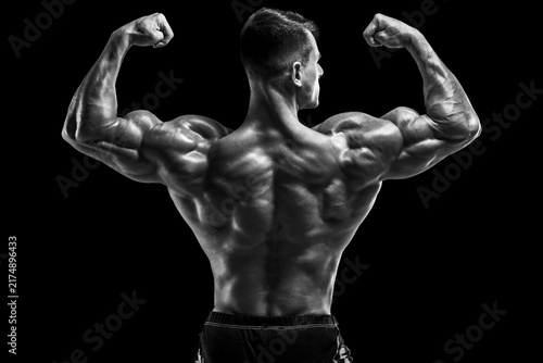Muscular man showing back muscles on black background. Strong male rear view