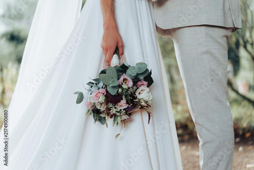 Foto Bride holding flower bouquet standing next to groom close up