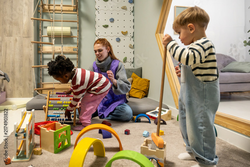 Teacher and multi ethnic children playing with Montessori toys in a classroom