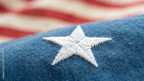 Macro shot of white embroidered star on blue fabric of United States flag with blurred background