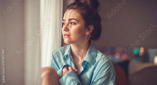 Woman Gazing Out Window with Light Filtered Through Curtains
