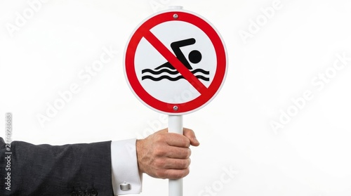 Hand in suit holding a no swimming prohibition sign isolated on white