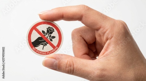 Hand holding a circular sticker with a no picking flowers prohibition sign