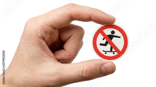 Hand holding a circular no skateboarding prohibition sign isolated on white