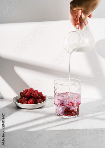 Fresh raspberry puree with milk on a light background.