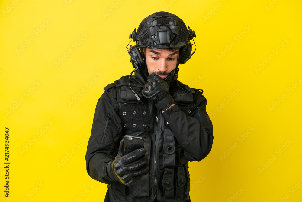 Fototapeta premium SWAT caucasian man isolated on yellow background thinking and sending a message