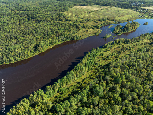 Aerial view of a winding river meandering through green taiga forest and fields near Kindasovo village in Karelia, Russia