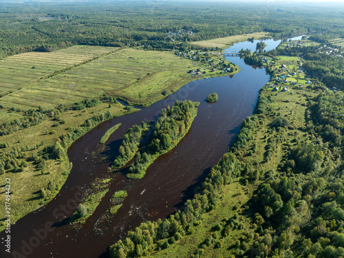 Aerial view of a winding river meandering through green taiga forest and fields near Kindasovo village in Karelia, Russia