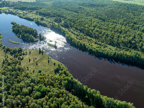 Aerial view of a winding river meandering through green taiga forest and fields near Kindasovo village in Karelia, Russia