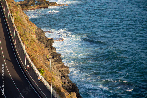 Persone che passeggiano su strada accanto a lungomare roccioso